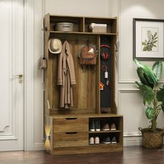 an open wooden cabinet with shoes and hats on it next to a potted plant