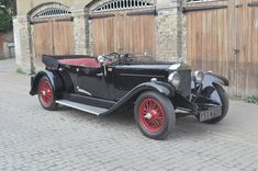 an old black car parked in front of a building