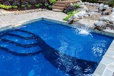 a blue swimming pool surrounded by rocks and plants