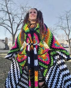 a woman with dreadlocks wearing a multicolored crocheted coat and skirt