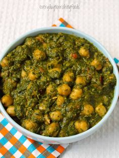 a bowl filled with spinach and chickpeas on top of a checkered napkin