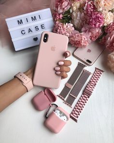 a person holding an iphone case next to some flowers and other accessories on a table