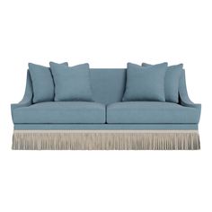 a light blue couch with fringed pillows on it's arms and backrests