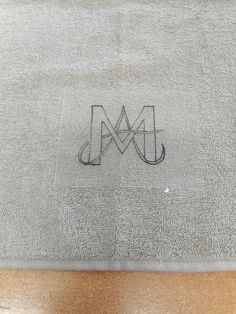 the monogrammed towel is on top of a wooden table with a black and white logo