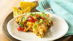 a white plate topped with an enchilada and chips