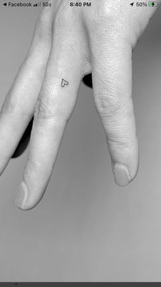 a person's left hand with a small heart tattoo on the middle finger,