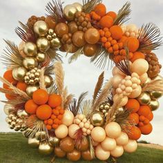 a wreath made out of balloons and other items on the grass with sky in background