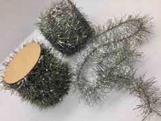 three silver tinsel brushes are on a white surface