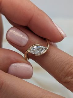 a close up of a person's hand holding a ring with a diamond on it