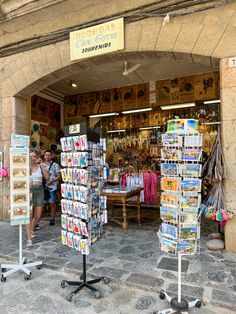 two people standing in front of a store with magazines on the shelves and other items for sale