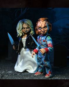 two dolls dressed as zombies holding knives and looking at each other while standing in front of a grave