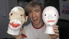 a man holding two fake masks with faces painted on them