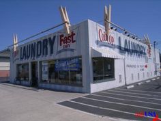 an empty parking lot in front of a laundry day store with clothes hanging from the roof