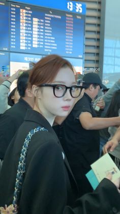 a woman with glasses is standing in an airport