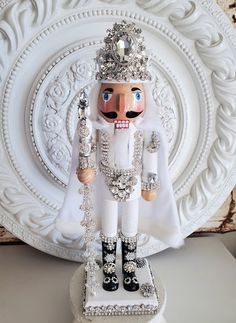 a nutcracker is standing in front of a white plate with ornate designs on it