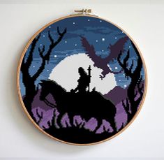 a cross stitch pattern with a silhouette of a man and woman on a horse in front of a full moon