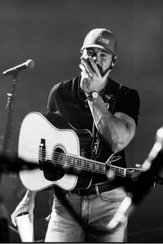 a man holding a guitar while singing into a microphone