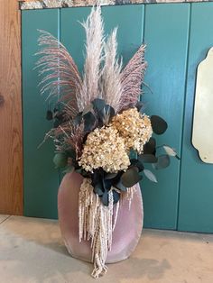 a vase filled with lots of flowers on top of a counter next to a blue wall