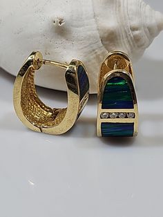 These stunning 14kt yellow gold earrings feature a beautiful black opal and eight diamonds with a total carat weight of .24ct. The opal is a gorgeous shade of blue and is cut to a very good grade. The earrings are cuff style and measure 3/4 inch in length. The diamonds have a slight inclusion clarity grade (SI2) and are secondary to the main opal stone. These earrings are perfect for any occasion and would make a great addition to anyone's jewelry collection. Wt.17.20 grams Elegant Opal Huggie Earrings, Elegant Opal Huggie Jewelry, Yellow Gold Earrings, Opal Stone, Yellow Gold Earring, Fine Jewellery Earrings, Black Opal, Shades Of Blue, Gold Earrings