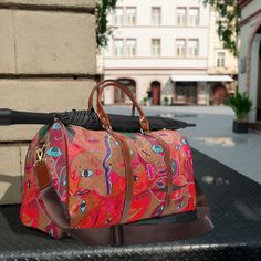 Immerse yourself in a travel experience like no other with this exceptional weekender bag, designed by none other than Melvin Lunkins. Yes, that's me! This isn't just a bag--it's a unique canvas of art, a reflection of personal style and functionality. Crafted from 100% high-grade, waterproof PU leather, the bag is both durable and easy to clean. Inside, a spacious main compartment and multiple smartly-designed pockets await. Secure your belongings with a chic, gold-colored zipper. Enjoy carrying comfort with brown PU leather handles and an adjustable shoulder strap. There's no need to choose from various colors or add initials; each bag comes with a singular, unique design inspired by my own canvas art. Don't just travel; make each journey a masterpiece. Order yours today! Red Weekender Bag For Travel, Brown Canvas Travel Bag For Trips, Red Travel Bag With Leather Handles, Red Rectangular Weekender Bag For Trips, Red Travel Bag With Adjustable Strap, Canvas Weekender Bag With Luggage Sleeve For Trips, Red Rectangular Weekender Bag For Travel, Canvas Tote Weekender Bag For Trips, Canvas Bags With Luggage Sleeve For Trips