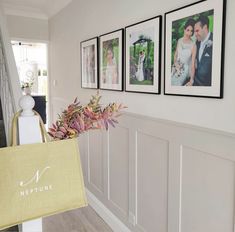 three framed pictures hang on the wall next to a vase with flowers in it and a yellow shopping bag