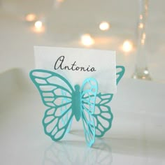 there is a small butterfly on top of a table with a name tag in it