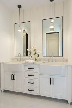 a bathroom with double sinks and two mirrors on the wall next to eachother