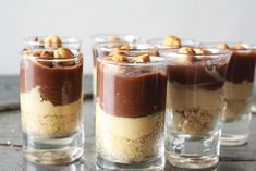 four desserts in small glass cups on a table