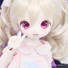 a close up of a doll with blonde hair and big eyes wearing a pink dress