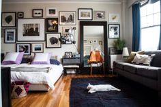 a living room filled with furniture and framed pictures on the wall above a bed in front of a mirror