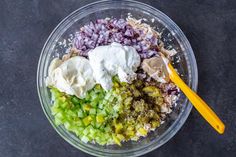 the ingredients for this salad are mixed together in a glass bowl with a yellow spoon