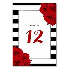 a table number card with red roses on black and white striped paper in the center