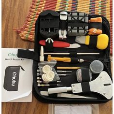 the contents of a tool bag sitting on top of a wooden floor next to a rug