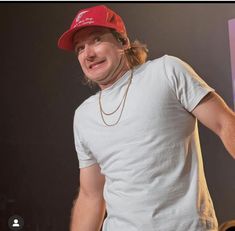 a man with long hair wearing a red hat and holding a microphone in his hand