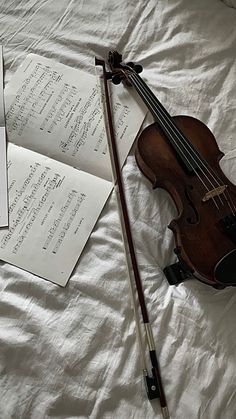 an old violin is laying on the bed next to some music sheets and a pair of scissors