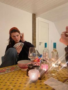 a woman sitting at a table with wine glasses and cards in front of her,