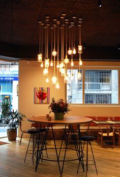 a dining room table and chairs with lights hanging from the ceiling