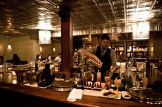 a man is preparing food in a restaurant bar with many bottles and glasses on the counter