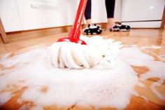 a person is cleaning the floor with a red mop and white cloth on it