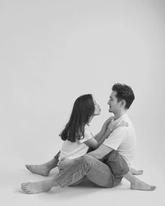 a man and woman sitting next to each other in black and white, looking at each other