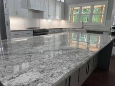 a large kitchen with white cabinets and marble counter tops