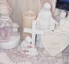 there are many figurines and candles on the table with white lace around them