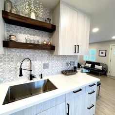 a kitchen with white counter tops and wooden shelves above the sink, along with open shelving