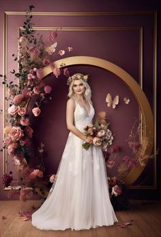 a woman standing in front of a purple wall with flowers and butterflies around her head