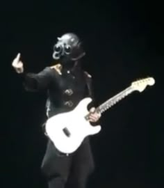 a man wearing a black mask and holding a white guitar