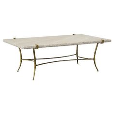 a white marble top coffee table with gold metal frame legs and two square shaped bases