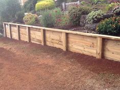 a long wooden fence in the middle of a yard with lots of flowers on it