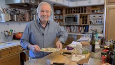 a man standing in a kitchen holding a plate with food on it