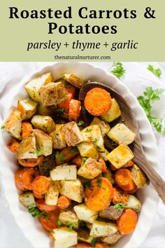 roasted carrots and potatoes in a white bowl with a wooden spoon on the side