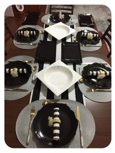 the table is set with black and white plates, silverware, and striped napkins